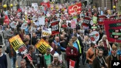 Demonstrators hold placards as they march during a protest against the Conservative Government and it's austerity policies in London, June 20, 2015. 