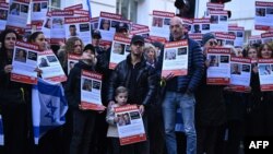 (FILE) People hold up posters of the missing as they gather to demand the release of the estimated 230 hostages held in Gaza by Hamas.