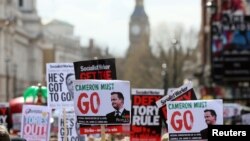 Demonstrators hold placards during a protest outside Downing Street in Whitehall, central London, April 9, 2016. 