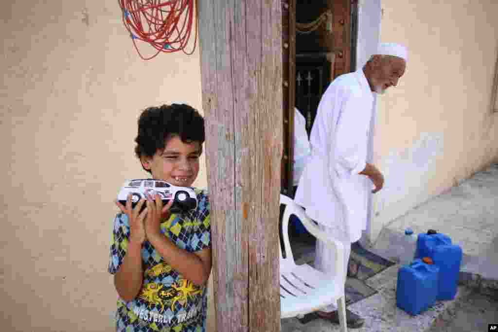 A boy plays outside while an old man brings containers of water into his house. Parts of Tripoli have been without running water for days. August 27,2011 (VOA - J. Weeks)