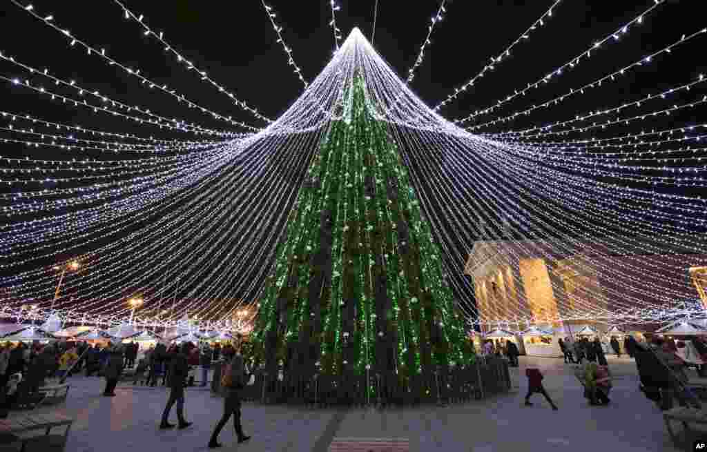 People stroll around a National Christmas tree at Cathedral square in Vilnius, Lithuania, Dec. 6, 2016.