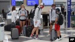 Travelers wearing maskes talk in a terminal at O'Hare International Airport, in Chicago, Illinois, Nov. 20, 2020. 