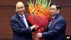 Vietnamese newly elected President Nguyen Xuan Phuc, left, and newly elected Prime Minister Pham Minh Chinh pose for a photo in the National Assembly in Hanoi, Vietnam on Monday, April 5, 2021. (Hoang Thong Nhat/VNA via AP)