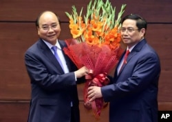 Vietnamese newly elected President Nguyen Xuan Phuc, left, and newly elected Prime Minister Pham Minh Chinh pose for a photo in the National Assembly in Hanoi, Vietnam on Monday, April 5, 2021. (Hoang Thong Nhat/VNA via AP)