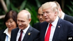 U.S. President Donald Trump, right, and Russia's President Vladimir Putin, center, talk during a group photo session at the APEC Summit in Danang, Vietnam, Nov. 11, 2017.