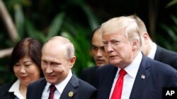 FILE - U.S. President Donald Trump, right, and Russia's President Vladimir Putin, center, talk during a group photo session at the APEC Summit in Danang, Nov. 11, 2017.