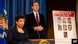 Attorney General Loretta Lynch, and FBI Director James Comey stand by a wanted poster of Iranians who are wanted by the FBI for computer hacking during a news conference at the Justice Department in Washington, Thursday, March 24, 2016.