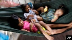 Cambodian children lay in a hummock for sleeping at the sidewalk as swinging by their mother in Phnom Penh, file photo. 