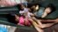 Cambodian children lay in a hummock for sleeping at the sidewalk as swinging by their mother in Phnom Penh, file photo. 