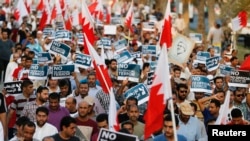 FILE - Anti-government protesters holding Bahraini flags and signs saying "No To Official Terror" march during a rally organized by Bahrain's main opposition party Al Wefaq on Budaiya highway west of Manama, August 23, 3013.