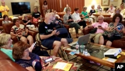FILE - Community activists learn how to register voters on their phones at a democratic Stand Indivisible AZ monthly meeting in Scottsdale, Ariz., as they strategize about upcoming midterm elections, July 16, 2018.