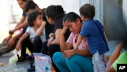 ARCHIVO - En esta foto de archivo del 16 de julio de 2019, migrantes esperan en un centro migratorio en el Puente Internacional 1 en Nuevo Laredo, México.