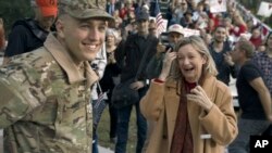 In this undated photo provided by Anheuser-Busch, Lt. Chuck Nadd, left, is greeted by his mother after he rode aboard the famously-red Budweiser beer wagon in a parade, led by a marching band through Winter Park, Fla. 