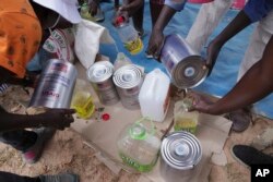 FILE—Women share cooking oil during a food distribution Mangwe district in southwestern Zimbabwe, March, 22, 2024.