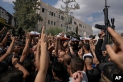 Mourners, some armed, carry the bodies of Palestinian men who were killed during an Israeli military operation, draped in the Islamic Jihad militant group flags, during their funeral in Jenin, West Bank, Sept. 6, 2024.