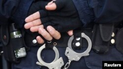 FILE - A Turkish riot police officer's handcuffs are pictured at the entrance of a courthouse in Istanbul. Turkish police say some of the Islamic State-linked suspects arrested in connection to a foiled terror plot over the weekend are foreign born.