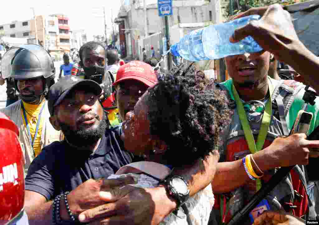 Journalists help a colleague who fainted after police threw tear gas during a protest against Haiti&#39;s President Jovenel Moise, in Port-au-Prince, Feb. 10, 2021.