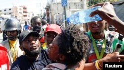 Jounalis ki t ap ede yon kolèg ki te endispoze apre lapolis te tire gaz lakrimojèn sou yon foul ki t ap manifeste kont Prezidan Jovenel Moise nan Pòtoprens, Ayiti, nan dat 10 fevriye 2021.
