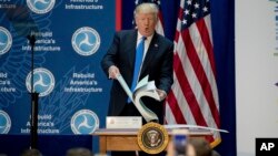 President Donald Trump shows the size of road planning documents for a highway plan in Maryland while speaking at the Department of Transportation in Washington, June 9, 2017.