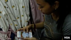 Soung Pisey, a clothes seller in Takmao market, Kandal province, Cambodia, is showing her Facebook account of the latest fashion online to her regular customers in early October 2017. (Khan Sokumnono/VOA Khmer)