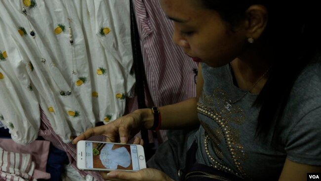 Soung Pisey, a clothes seller in Takmao market, Kandal province, Cambodia, is showing her Facebook account of the latest fashion online to her regular customers in early October 2017. (Khan Sokumnono/VOA Khmer)