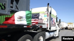 FILE - A truck of the Mexican company Olympics bearing Mexican and U.S. flags approaches the border crossing into the U.S., in Laredo.