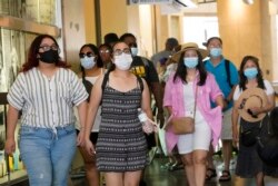 Visitors wear masks as they walk in a shopping district in the Hollywood section of Los Angeles.