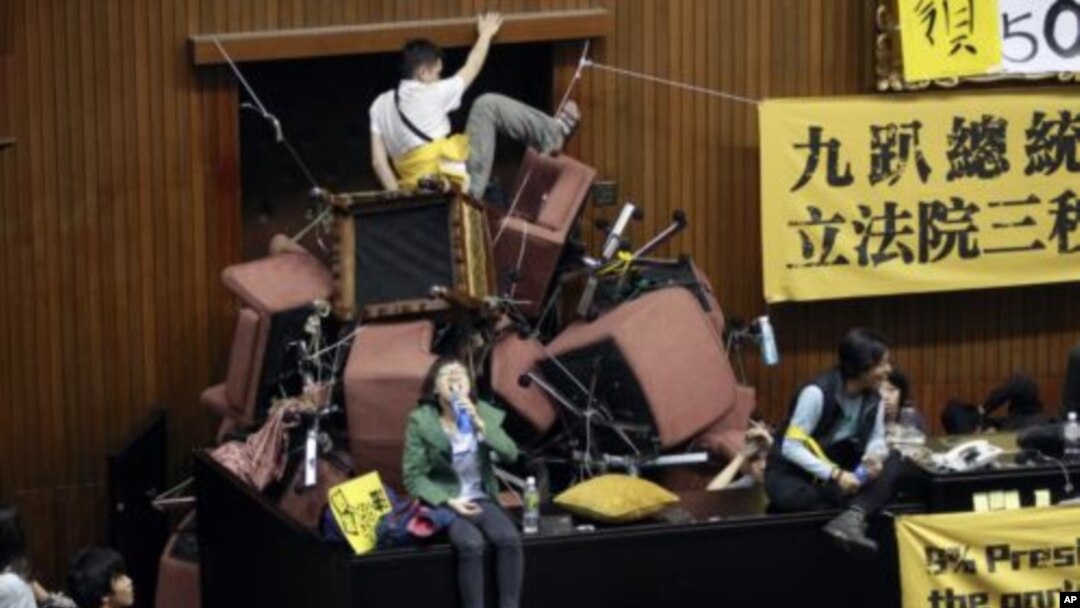 Demonstran Taiwan menumpuk kursi di ruangan parlemen agar tidak dapat dimasuki polisi. 