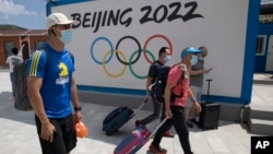 到河北省张家口崇礼的游客走过北京2022冬季奥运会的广告牌。（2020年8月13日）