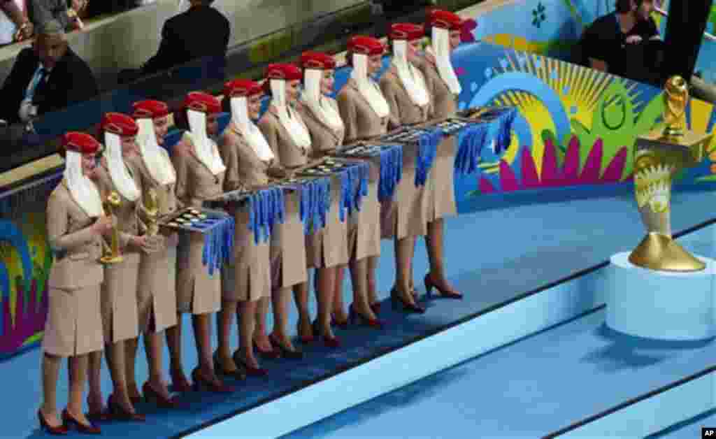 Barisan perempuan pembawa medali berdiri dekat trofi Piala Dunia usai pertandingan final antara Argentina dan Jerman yang dimenangkan tim panser di stadion Maracana di Rio de Janeiro, Brazil, Minggu (13/7). (AP/Francois Xavier Marit)