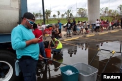 Local residents wait in line during a water distribution in Bayamon following damage caused by Hurricane Maria in Carolina, Puerto Rico, Sept. 30, 2017.