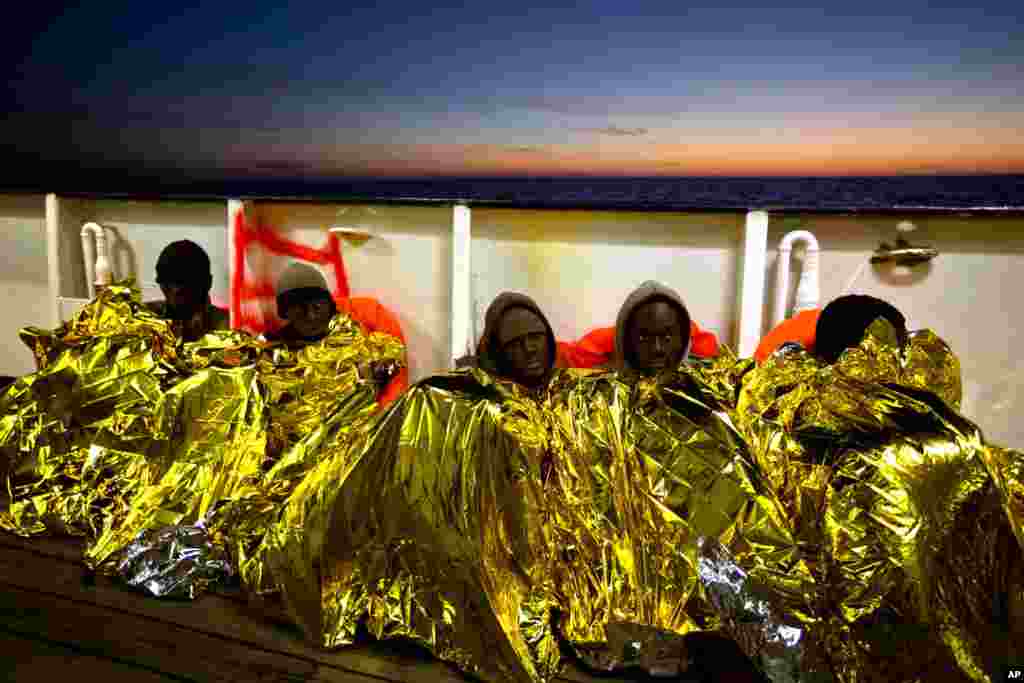 Sub-Saharan migrants cover themselves with a heating blanket on the deck of the Golfo Azzurro after been rescued from the Mediterranean sea, about 24 miles north of Sabratha, Libya. Rescuers pulled nearly 300 people from two rubber boats in waters off the coast and were looking for 100 more believed to be on another boat missing since Sunday.