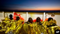 FILE - Sub-Saharan migrants cover themselves with a heating blanket at the deck of the Golfo Azzurro boat after been rescued from a rubber boat by members of Proactive Open Arms NGO, at the Mediterranean sea, north of Sabratha, Libya, Jan. 27, 2017.