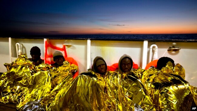 FILE - Sub-Saharan migrants cover themselves with a heating blanket at the deck of the Golfo Azzurro boat after been rescued from a rubber boat by members of Proactive Open Arms NGO, at the Mediterranean sea, north of Sabratha, Libya, Jan. 27, 2017.