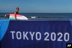 Surfer Carissa Moore of the United States heads into the water for a practice run at Tsurigasaki beach at the Tokyo 2020 Olympics, in Ichinomiya, Japan, July 21, 2021.