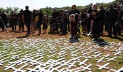 FILE - People place crosses, representing white farmers killed in South Africa, at a ceremony at the Vorrtrekker Monument in Pretoria, Oct. 30, 2017.