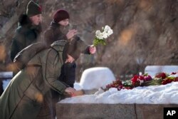 People pay their last respects to Alexey Navalny at the monument, a large boulder from the Solovetsky islands, where the first camp of the Gulag political prison system was established, in Moscow, Russia, Feb. 20, 2024.