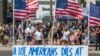 Des gens traversent la rue devant un panneau de protestation contre le système de santé, à Huntington Beach, en Californie, le 19 juillet 2020 au milieu de la pandémie de coronavirus.