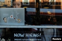 FILE - A "Now Hiring" sign sits in the window of a bakery-cafe in Cambridge, Massachusetts, Feb. 11, 2019.