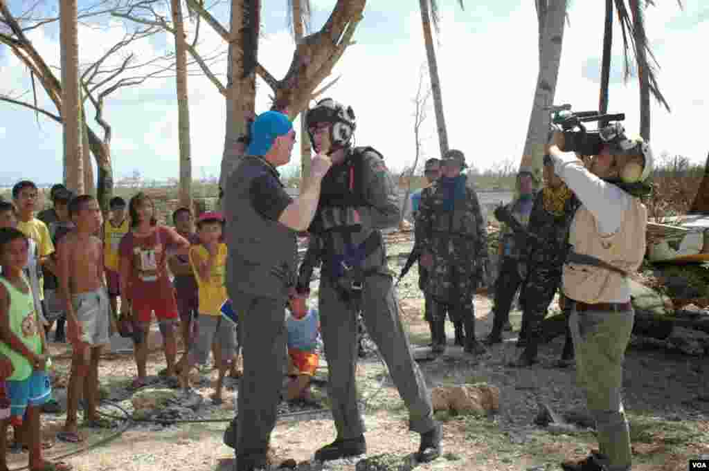 An American NGO worker pleads with a U.S. Navy helicopter crewman to bring more aid as VOA videographer Zinlat Aung videotapes the encounter in Hernani, Philippines, Nov. 19, 2013. (Steve Herman/VOA) 