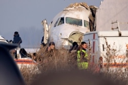 Police stand guard as rescuers assist on the site of a plane crash near Almaty International Airport, outside Almaty, Kazakhstan, Dec. 27, 2019. The Kazakhstan plane with 98 people aboard crashed shortly after takeoff early Friday.