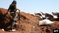 A Syrian rebel carries his machine gun during battles with pro-government fighters in western Daraa province, July 10, 2018. 