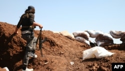 A Syrian rebel carries his machine gun during battles with pro-government fighters in western Daraa province, July 10, 2018. 