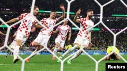 Josko Gvardiol dari Kroasia, Ante Budimir, Dejan Lovren, dan Lovro Majer merayakan kemenangan Kroasia ke semi final saat Marquinhos dari Brasil terlihat sedih setelah gagal mengeksekusi penalti dan tersingkir dari Piala Dunia. (Foto: REUTERS/Matthew Childs)