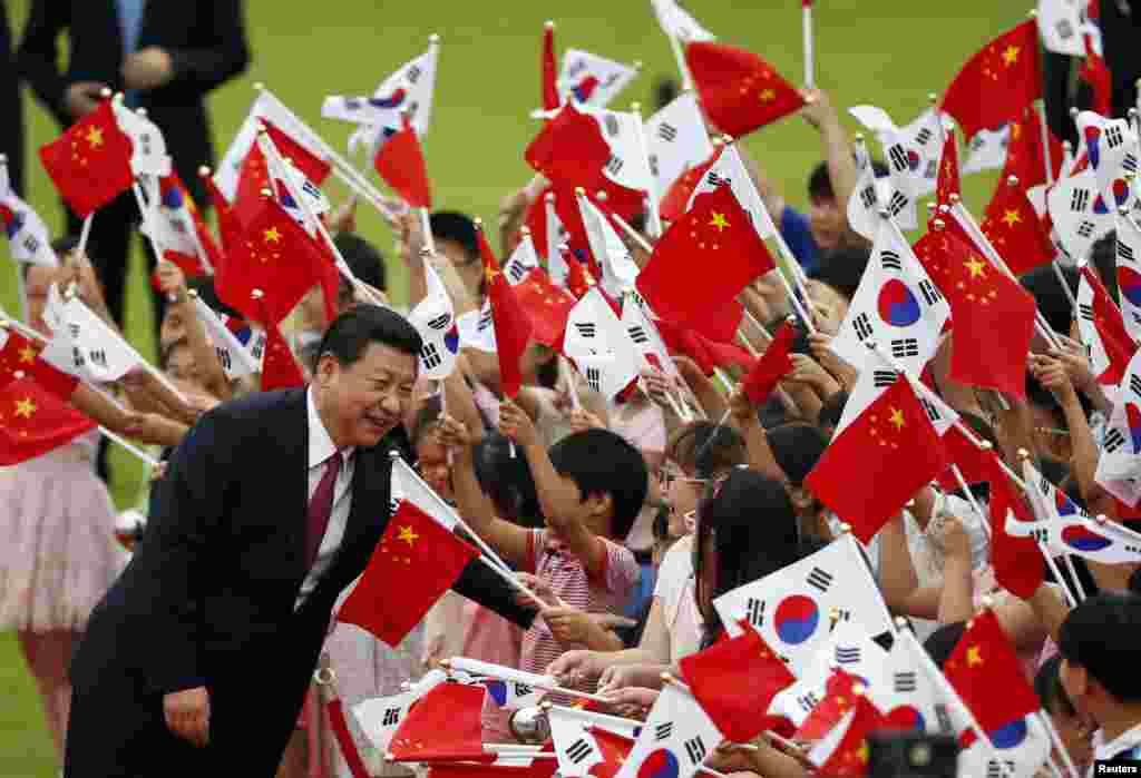 Presiden China, Xi Jinping menyalami anak-anak yang menyambut kedatangannya di Seoul, Korea Selatan.