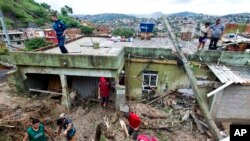 Locals work to clean up mud and debris around houses destroyed by a landslide after heavy rains in Vila Ideal neighborhood, Ibirite municipality, Minas Gerias state, Brazil, Jan. 25, 2020.
