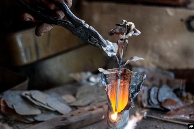 Mikhalev is transforming weapons and ammunition into flowers of war. Mikhalev, trained as a welder, lives and works in a house whose fence and door are decorated with forged flowers and grapes. (AP Photo/Alexei Alexandrov)