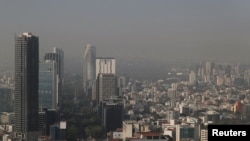 Vista general de edificios y casas en medio de la contaminación en la Ciudad de México, México, 6 de diciembre de 2024. Fotografía tomada a través de una ventana de vidrio de un edificio. 