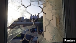 Israelis are seen through a window damaged after a rocket fired from the Gaza Strip landed in the southern town of Ofakim, November 18, 2012. 