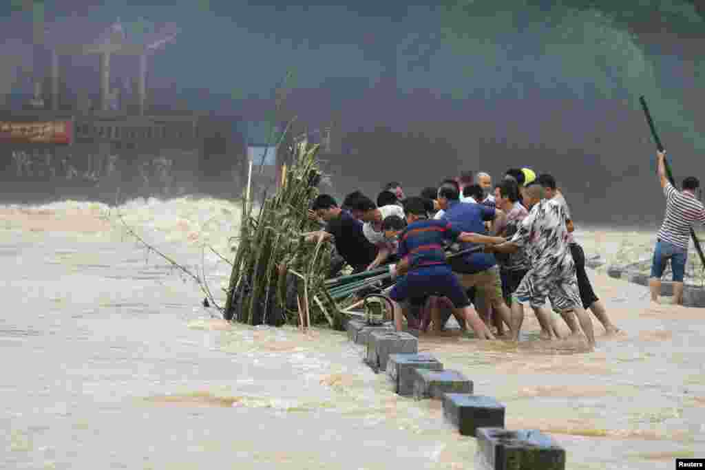 People remove a bunch of bamboos from a bridge in floodwaters following heavy rainfall in Rongan county, Liuzhou, Guangxi Zhuang Autonomous Region, China, June 10, 2019.